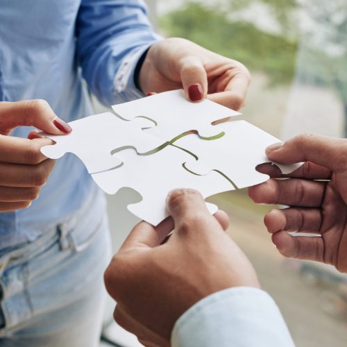 Close-up image of business people assembling puzzle